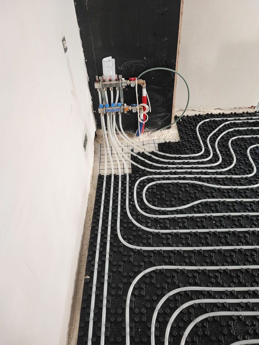 Collector van een vloerverwarming met leidingen op noppenplaat