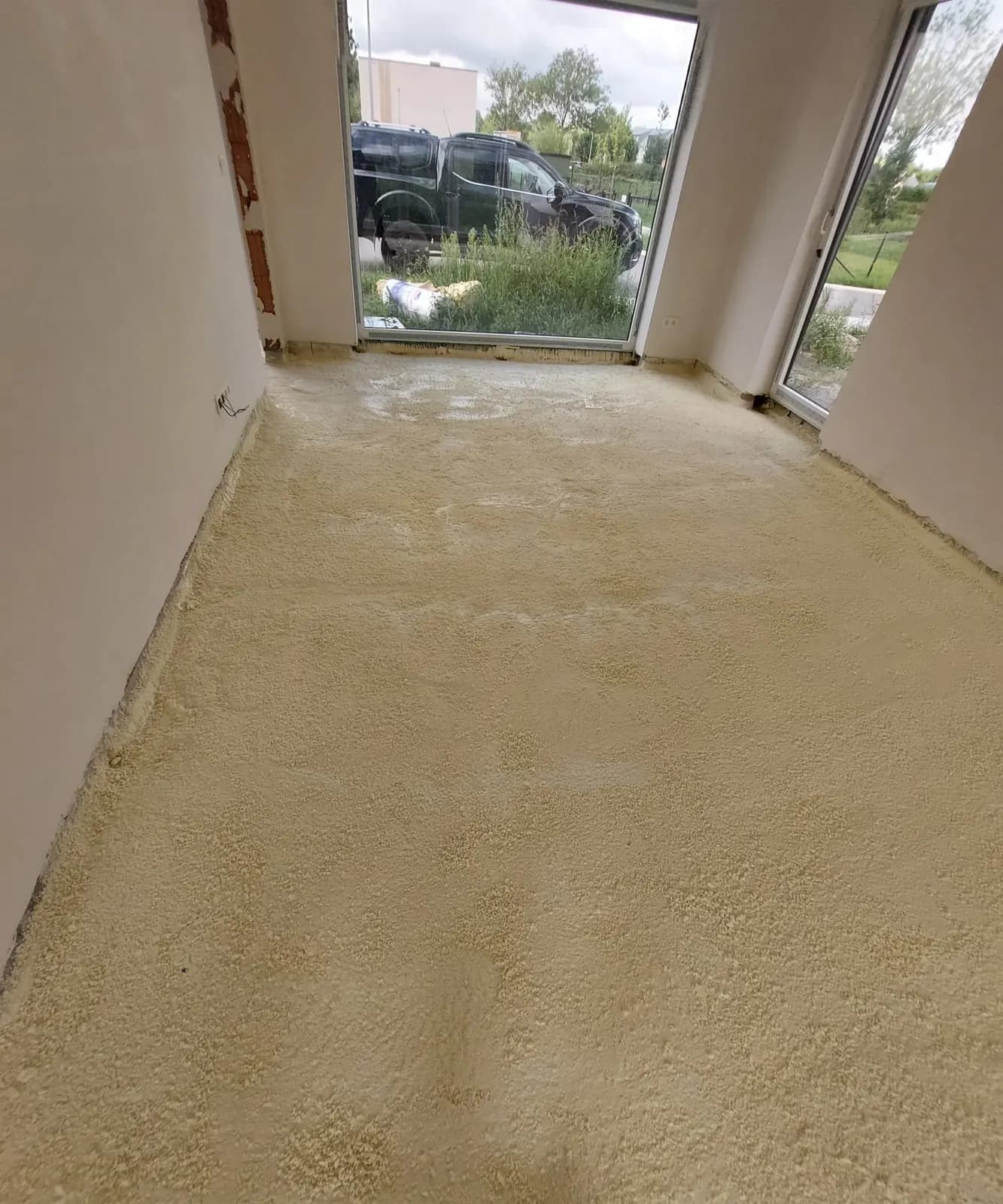 Afgewerkte gespoten PUR-vloer in een nieuwbouwkamer met groot raam