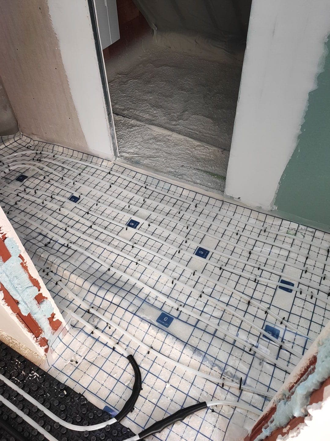 Vloerverwarmingsbuizen vastgezet op een net bij een deuropening